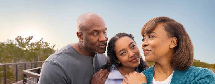 Actor portrayal of TUKYSA (tucatinib) patient with loved ones standing together on an outdoor walkway looking at each other.