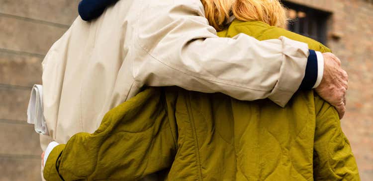 Actor portrayal of two people wearing jackets with their arms around each other