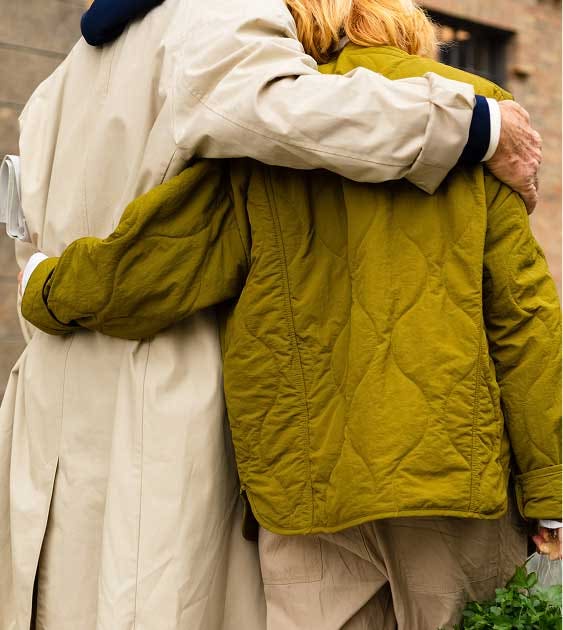 Actor portrayal of two people wearing jackets with their arms around each other